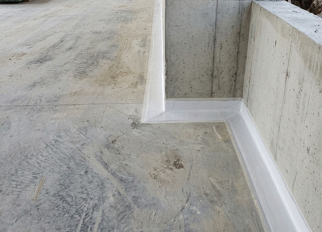 The coating forms a continuous protective barrier around the perimeter, including the internal corner and recessed section. Careful detailing at these wall-to-floor transitions helps reduce the risk of water penetration through vulnerable construction joints and concrete interfaces.