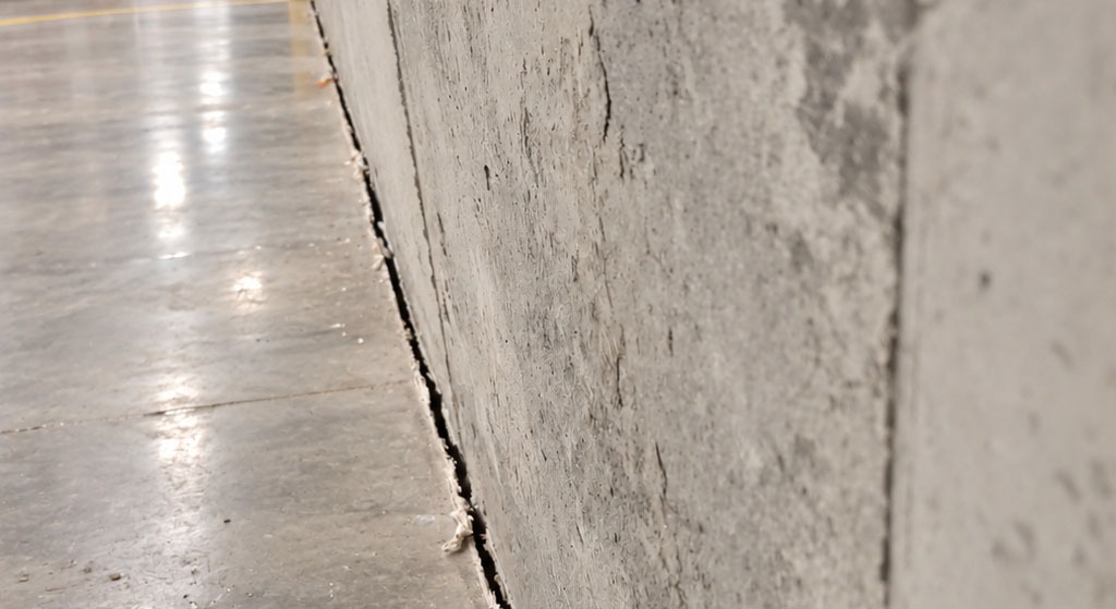 Gaps like this are commonly found where horizontal concrete slabs meet vertical walls, particularly in warehouses, industrial buildings, basements, commercial facilities, and newly constructed structures. They may be intentionally incorporated to accommodate slight movement between different building elements, or they may become more pronounced over time due to concrete shrinkage, thermal expansion and contraction, settlement, vibration, or differential movement between the floor and wall.